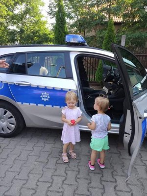 dwie małe dziewczynki stoją przy policyjnym radiowozie