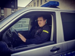 umundurowany policjant siedzi za kierownicą radiowozu