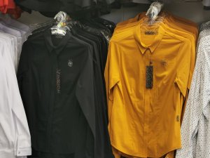 Koszule w kolorze czarnym i musztardowym wiszą na wieszakach