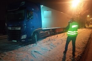 Na zdjęciu widać pojazd ciężarowy koloru niebieskiego z podłączoną naczepą. Przez zespołem pojazdów stoi technik kryminalistyki ubrany w żółtą kamizelkę z napisem policja i wykonuje zdjęcie.