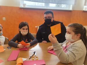 Policjant siedzi przy stole z dziećmi obok niego.