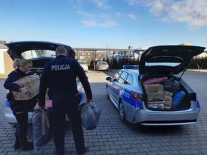 policjantka i policjant pakują zgromadzone dary do radiowozów