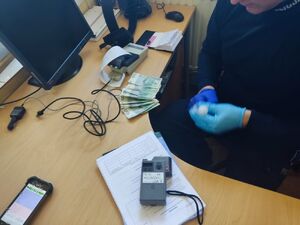 Policjant siedzi za biurkiem, przed nim siedzi zatrzymany mężczyzna.