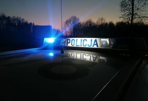 sygnalizator świetlny na dachu radiowozu z napisem Policja z migającym światłem niebieskim