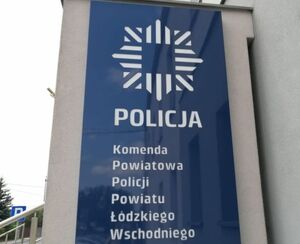 Szyld na budynku komendy na granatowym tle napis Komenda Powiatowa Policji powiatu łódzkiego wschodniego.
