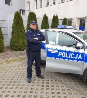 Policjant stoi przy radiowozie.