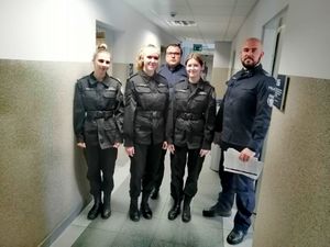 Trzy uczennice stoją na korytarzu przy dwóch umundurowanych policjantach.