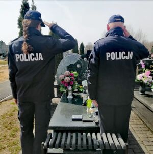 Policjanci stoją przy grobach na cmentarzu.
