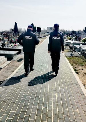 policjanci stoją przy grobach na cmentarzu