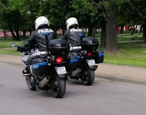 policjanci jadą na służbowych motocyklach, z białymi kaskami na głowach