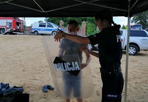 policjanci i strażacy na spotkaniu z młodzieżą przy zbiorniku wodnym na plaży