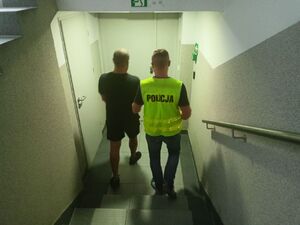 policjanci prowadzą zatrzymanego mężczyzn w krótkich spodenkach