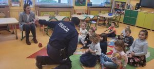 Policjant jest przy grupie dzieci siedzących na dywanie