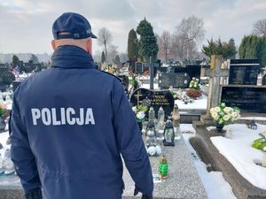 Policjant stoi przy grobie na cmentarzu.