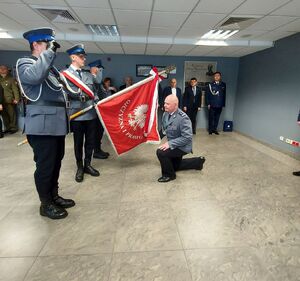 Komendant klęka przed sztandarem policji powiatu łódzkiego wschodniego.