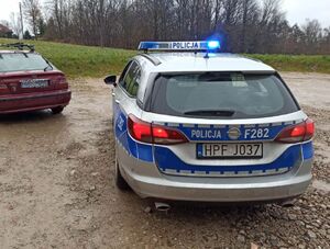 radiowóz stoi zaparkowany przy stojącym obok czerwonym samochodzie