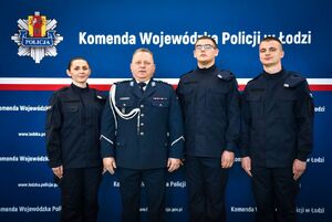 Czterech policjantów w granatowych mundurach stoją w rzędzie obok siebie.