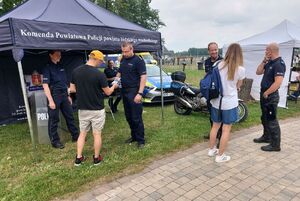 Policjanci rozmawiają z kobietą i mężczyzną, którzy do zdjęcia odwróceni są tyłem, policjanci się uśmiechają.