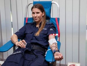 Policjantka oddaje krew siedząc na fotelu.