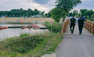 Strażak i policjant wchodzą na most przy zbiorniku wodnym.
