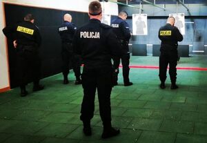 Policjanci stoją odwróceni tyłem i przygotowują się do strzelania w tarcze ustawione przed nimi.
