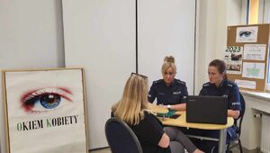 Dwie policjantki w mundurach siedzą przy stoliku, przed nimi siedzi kobieta o blond włosach.