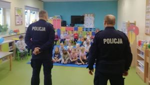 Dwóch policjantów stoi na środku sali, przed nimi siedzą dzieci.