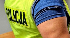 Policjant w żółtej kamizelce z napisem policja.