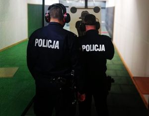 Dwóch policjantów stoi przy tarczy do strzelania.