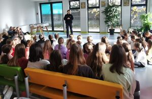 Policjantka stoi na środku sali, przed nią siedzi duża grupa młodych ludzi.