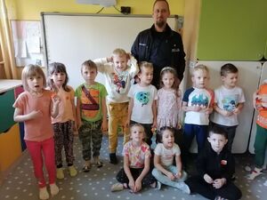 Policjant stoi przy grupie małych dzieci.