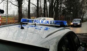 Sygnalizator na dachu radiowozu z napisem Policja i dwoma niebieskimi światłami po bokach.