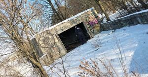 Policjant stoi przy opuszczonym budynku.