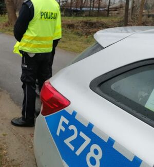 Dwóch policjantów stoi przy radiowozie.