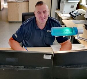 Policjant siedzi za biurkiem.