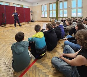 Policjantka stoi na środku sali i rozmawia z uczniami.