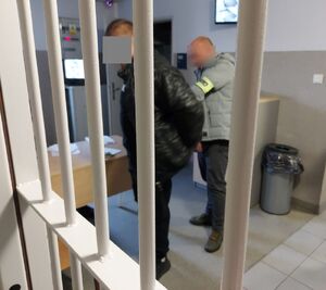 Policjant zapina kajdanki zatrzymanemu mężczyźnie.