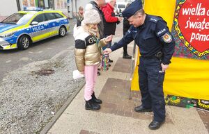 Policjant stoi przy wolontariuszach wośp.