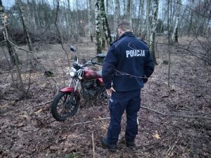 Policjant stoi przy czerwonym motocyklu.