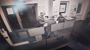 Policjant prowadzi zatrzymanego mężczyznę.