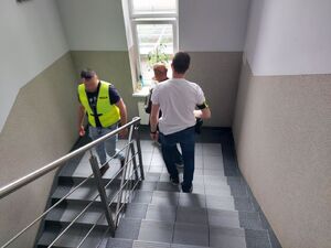 Dwóch policjantów prowadzi w środku zatrzymanego mężczyznę.