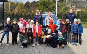 Policjant i policjantka stoją przy grupie ustawionych obok nich dzieci.