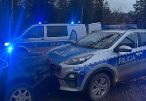 Dwa policyjne radiowozy z migającymi niebieskimi sygnalizatorami.