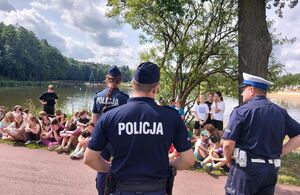 Dwóch policjantów i jedna policjantka stoją przed grupą młodych ludzi.