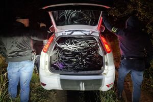 Dwóch policjantów stoi przy białym samochodzie, w którym otwarty jest bagażnik.