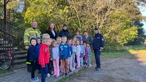 Policjantki i strażak wchodzą do budynku przedszkola, idą z wyprowadzanymi dziećmi.