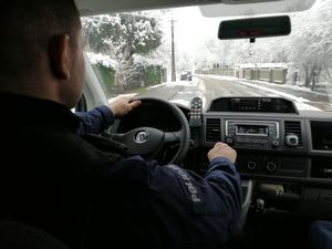 Policjant jedzie radiowozem, przed nim zaśnieżone ulice.