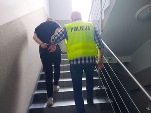 Policjant prowadzi zatrzymanego mężczynę.