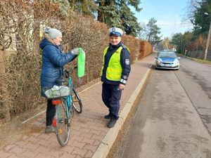 Policjant rozdaje kamizelki mieszkańcom.