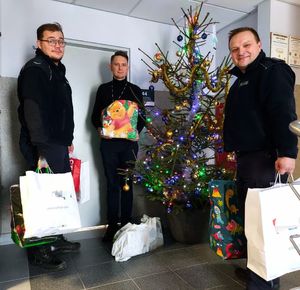 Trzech policjantów trzyma spakowane dary.